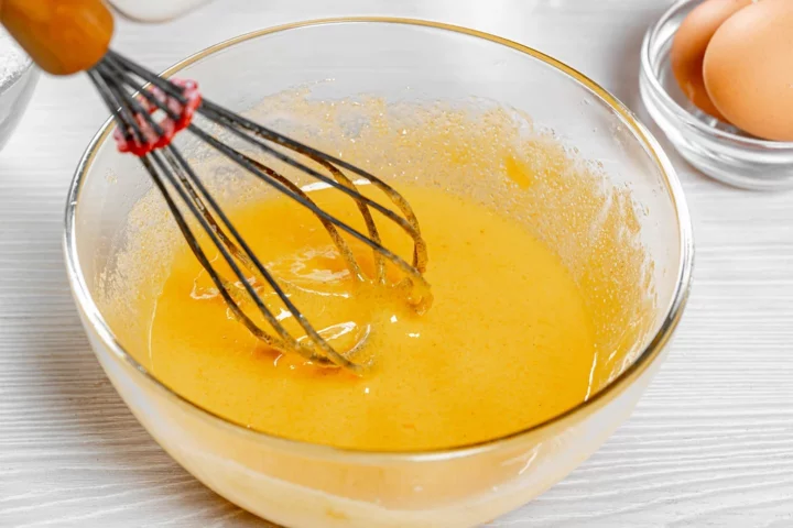 beaten eggs in a bowl with a whisk
